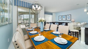 A dining area with a long wooden table set for four, blue placemats, and a vase with white flowers. - Beautiful 5 Star Townhome on Storey Lake Resort With Private Pool, Orlando Townhome 4889 (Kissimmee)