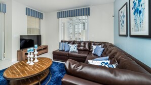 A modern living room with a brown leather sofa, a wooden coffee table, and a flat-screen TV. - Beautiful 5 Star Townhome on Storey Lake Resort With Private Pool, Orlando Townhome 4889 (Kissimmee)