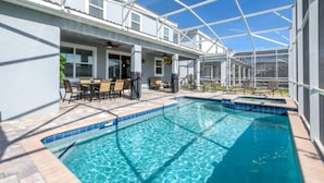 Ein Schwimmbecken mit Glasüberdachung, eine Terrassenfläche mit Stühlen und Tisch sowie ein überdachter Sitzbereich mit Deckenventilator.