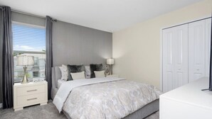 A bedroom with a bed, nightstands, a lamp, a wardrobe, and a window with curtains. - At Last You can Rent the Perfect Luxury Mansion on Champions Gate Resort, Minutes From Disney World, Orlando Mansion 3117 (Davenport)