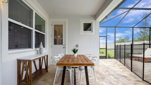 A patio with a wooden table and chairs, a small potted plant, and a view of the outdoors through a glass door. - Beautiful Mansion With Private Pool, Close to Disney, Orlando Mansion 3113 (Kissimmee)