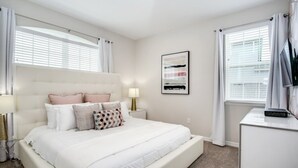 A bedroom with a large bed, a bedside table, a lamp, and a framed picture on the wall. - Beautiful Mansion With Private Pool, Close to Disney, Orlando Mansion 3113 (Kissimmee)