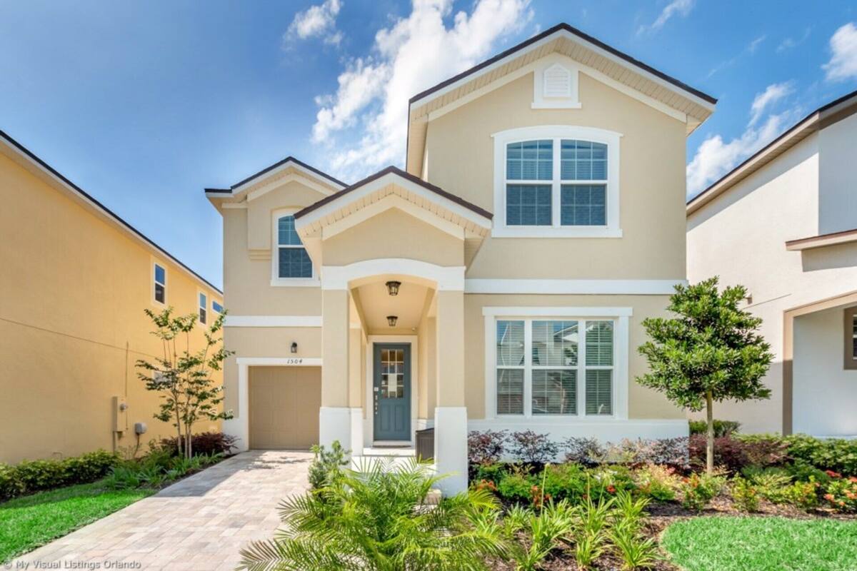 A two-story house with a front entrance, a covered porch, and a landscaped garden.