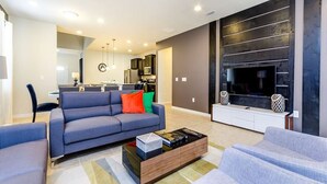 A modern living room with a grey sofa, a coffee table, and a TV against a dark wall. - Modern Oasis With 7 Bedrooms & Garden 5524 (Kissimmee)