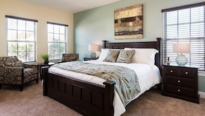 A bedroom with a large bed, two nightstands, a chair, and a window with blinds. - Beautiful Villa With First Class Amenities on Reunion Resort and Spa, Orlando Villa 4582 (Kissimmee)