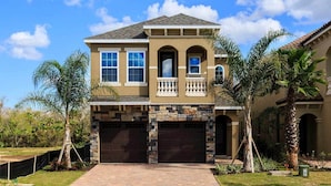 A two-story house with a stone facade, a balcony with balustrades, and a garage. - Beautiful Villa With First Class Amenities on Reunion Resort and Spa, Orlando Villa 4582 (Kissimmee)