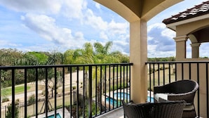 A balcony with a view of a swimming pool and palm trees. - Beautiful Villa With First Class Amenities on Reunion Resort and Spa, Orlando Villa 4582 (Kissimmee)