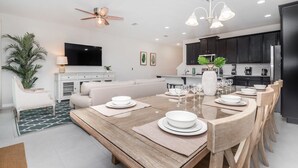A modern kitchen with dark cabinets, a stainless steel refrigerator, and a dining area with a wooden table set for six. - Exclusive Townhome With Large Private Pool on Solara Resort, Orlando Townhome 4831 (Kissimmee)