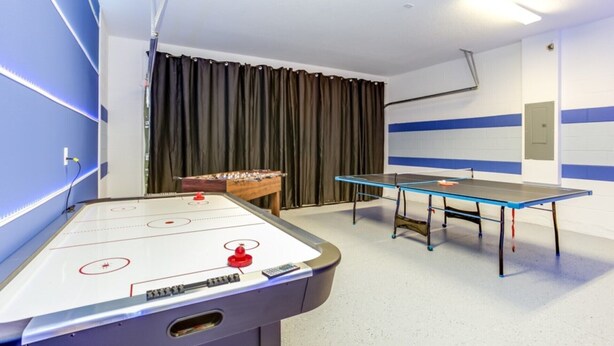 Una habitación con mesa de ping pong, mesa de fútbol de mesa y mesa de billar.