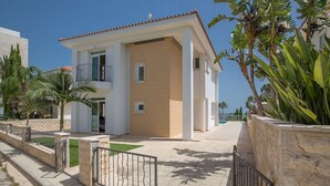 A modern two-story residential building with a balcony, a swimming pool, and a stone wall. - Beautiful Villa With Private Pool, Protaras Villa 1407 (Paralimni)