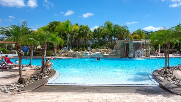 A swimming pool with a waterfall feature, surrounded by palm trees and lounge chairs. - Imagine You and Your Family Renting This 5 Star Villa on Paradise Palms Resort , Orlando Townhome 5537 (Kissimmee)