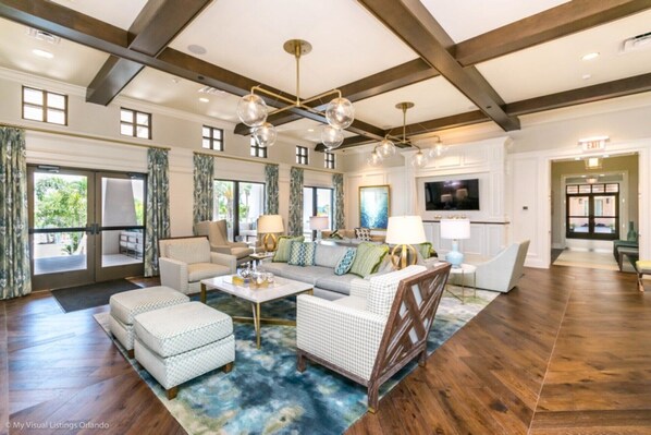 A spacious living room with a large sofa, ottomans, and a coffee table. There are multiple windows and a ceiling fan. - Beautiful Villa With Private Pool, Close to Disney, Orlando Villa 3124 (Kissimmee)