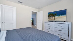 A bedroom with a bed, a dresser, and a television on the wall. - Tranquil Oasis With Lush Gardens 5496 (Davenport)