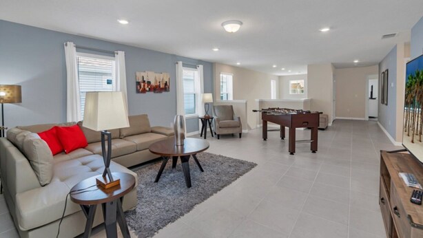A spacious living area with a sofa, coffee table, and a foosball table. - Tranquil Oasis With Lush Gardens 5496 (Davenport)