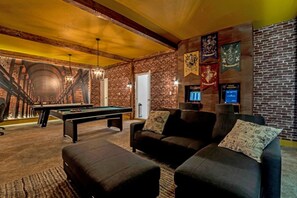 A billiards room with a pool table, a sofa, and a brick wall.