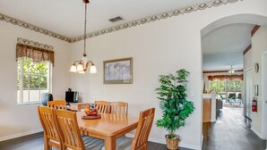 A dining area with a wooden table and chairs, a potted plant, and a painting on the wall. - Imagine Your Family Renting This Luxury Villa on Highlands Reserve, Orlando Villa 3607 (Davenport)