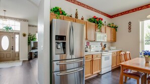 A modern kitchen with stainless steel appliances, wooden cabinets, and a dining area with a wooden table and chairs. - Imagine Your Family Renting This Luxury Villa on Highlands Reserve, Orlando Villa 3607 (Davenport)