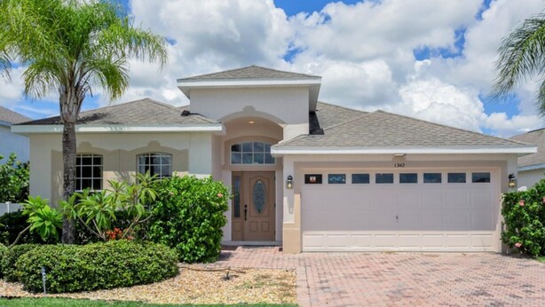 A two-story house with a garage, a front porch, and a well-maintained garden. - Imagine Your Family Renting This Luxury Villa on Highlands Reserve, Orlando Villa 3607 (Davenport)
