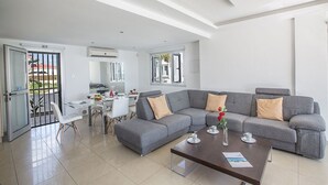 Una sala moderna con un sofá seccional gris, una mesa de centro y un comedor con una mesa y sillas blancas.