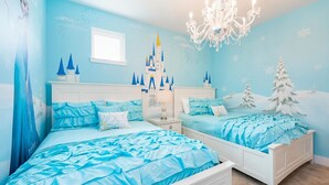 Ein Schlafzimmer mit zwei Betten, einer Kristallleuchtre und einer Wandmalerei mit Schlossmotiv.