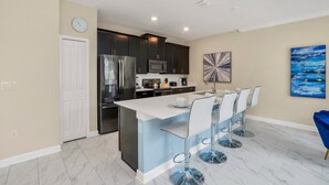 A modern kitchen with dark cabinets, a stainless steel refrigerator, and a central island with bar stools. - Imagine You and Your Family Renting This 5 Star Villa on Storey Lake Resort , Orlando Townhome 5519 (Kissimmee)