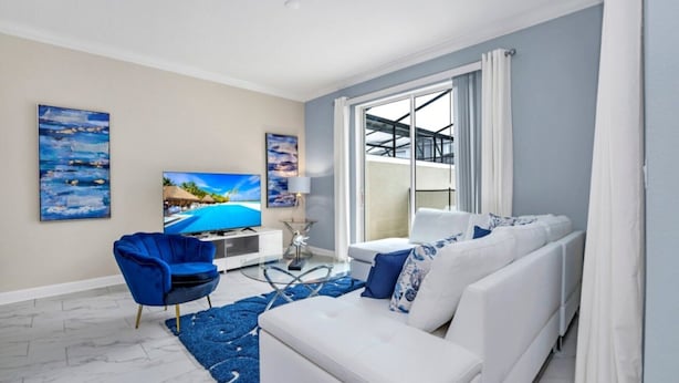 A modern living room with a white sofa, blue armchair, and a flat-screen TV. - Imagine You and Your Family Renting This 5 Star Villa on Storey Lake Resort , Orlando Townhome 5519 (Kissimmee)