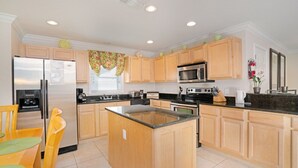 A kitchen with wooden cabinets, a stainless steel refrigerator, a microwave, and a stove. - Imagine You and Your Family Renting This 5 Star Villa on Providence Resort, Orlando Villa 3629 (Davenport)