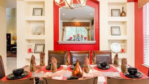 A dining area with a red and white color scheme, featuring a chandelier, framed certificates, and a mirror above the table. - Luxury 6 Bedroom Villa on Emerald Island Resort, Orlando Villa 1460 (Kissimmee)