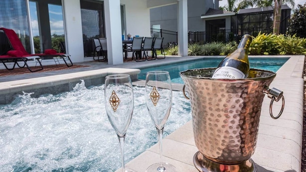 A poolside setting with a hot tub, two champagne glasses, and a copper ice bucket with a bottle of champagne. - Luxury Villa With Private Pool on Encore Resort at Reunion, Orlando Villa 4695 (Kissimmee)