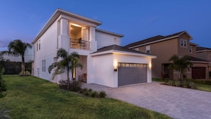 A modern two-story house with a balcony, a garage, and a well-maintained lawn. - Luxury Villa With Private Pool on Encore Resort at Reunion, Orlando Villa 4695 (Kissimmee)