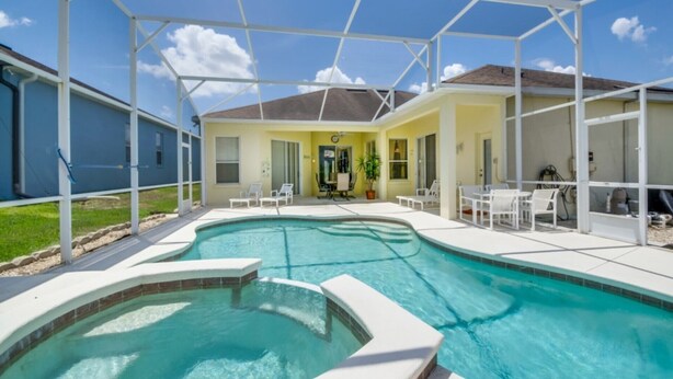 Une piscine dotée d’un patio couvert, le tout entouré d’une clôture blanche.