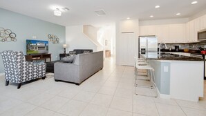 Een modern appartement met een woonkamer, keuken en een trap naar een hoger niveau.