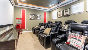 A home theater room with multiple reclining chairs, a popcorn machine, and framed pictures on the walls. - Luxury Villa on Reunion Resort and Spa, Orlando Villa 2501 (Kissimmee)