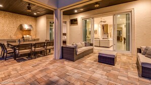 A spacious patio with a stone floor, a dining area with a table and chairs, and a seating area with a sofa and ottoman. - Luxury Villa on Reunion Resort and Spa, Orlando Villa 2501 (Kissimmee)