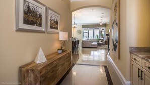 A spacious hallway with a wooden bench, framed artwork, and a dining area in the background. - Luxury Villa on Reunion Resort and Spa, Orlando Villa 2501 (Kissimmee)