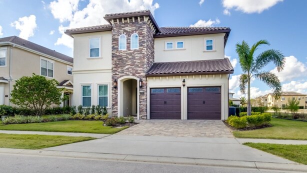A two-story house with a stone facade, a tiled roof, and a garage. - Luxury Villa on Reunion Resort and Spa, Orlando Villa 2501 (Kissimmee)