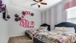 A bedroom with two beds, striped walls, a ceiling fan, and decorative wall art. - Luxury Villa on Reunion Resort and Spa, Orlando Villa 2501 (Kissimmee)