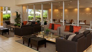 A spacious lobby with multiple seating areas, including sofas and armchairs, arranged around a central coffee table. Large windows provide natural light and views of the outdoors. - Perfect Townhome on Enchantada Resort Orlando Townhome 5495 (Kissimmee)