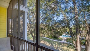 A porch with a table and chairs, overlooking a grassy area with trees and a distant swimming pool. - Luxury Home on Bahama Bay Resort,minutes From Disney World, Orlando Condo 5057 (Davenport)