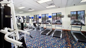 Un gimnasio con cintas de correr, elípticas y equipo de pesas.