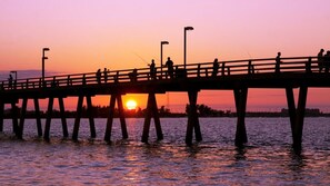 Un muelle con gente pescando al atardecer.