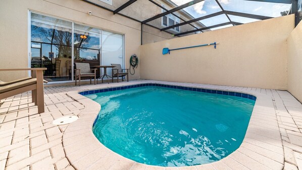 Una piscina con techo de cristal, rodeada por un patio con sillas y una mesa.