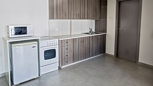 Een kleine keuken met een magnetron, oven en spoelbak.