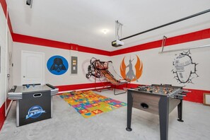 A room with a foosball table, a projector, and Star Wars-themed decorations.