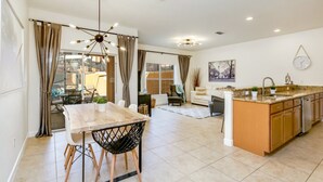 A spacious kitchen with a central island, a dining area with a wooden table and chairs, and a living area with a sofa and a coffee table. - You Have Found the Ultimate Luxury Townhome on Paradise Palms Resort, Orlando Townhome 3727 (Kissimmee)
