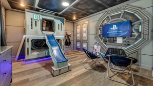 A room with a play area including a slide, Star Wars-themed decor, and a PlayStation TV.