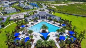 Un grand hôtel moderne doté d’une piscine centrale, de nombreuses chambres et d’une pelouse bien entretenue.