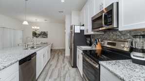 A modern kitchen with granite countertops, stainless steel appliances, and a backsplash. - Luxury Contemporary Style Townhome on Champions Gate Resort, Orlando Townhome 4935 (Davenport)