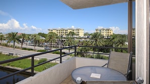 A balcony with a table and chair, overlooking a marina with yachts and a hotel in the background. - Perfect Apartment on The Anchorage, Siesta Key Apartment 1014 (Siesta Key)