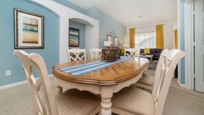 Een eetruimte met een houten tafel, witte stoelen en een blauw-gestreepte placemat.